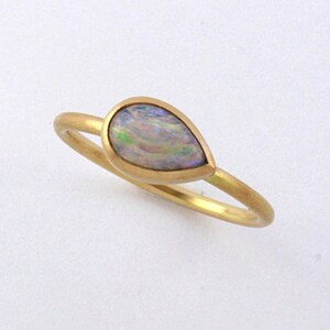 May include: A gold ring with a teardrop-shaped opal gemstone.