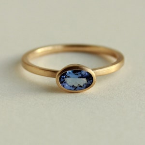 May include: A gold ring with a blue oval gemstone.