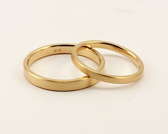 May include: Two gold wedding bands, one with the inscription "750" on the inside.