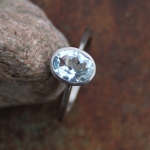 May include: A silver ring with a light blue oval aquamarine gemstone.