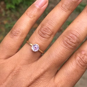 May include: A gold ring with a round, purple gemstone.