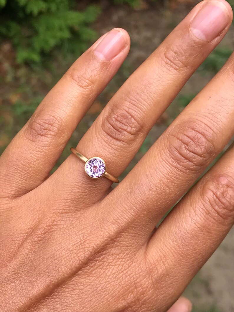 May include: A gold ring with a round, purple gemstone.