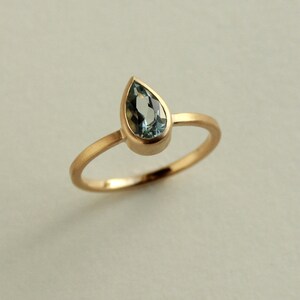 May include: A gold ring with a teardrop-shaped blue gemstone.