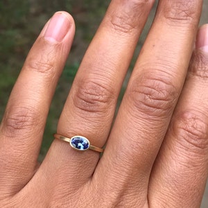 May include: A gold ring with a blue oval gemstone.