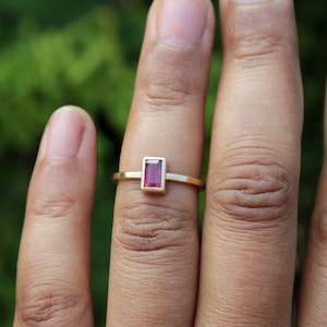 May include: A gold ring with a rectangular pink gemstone.