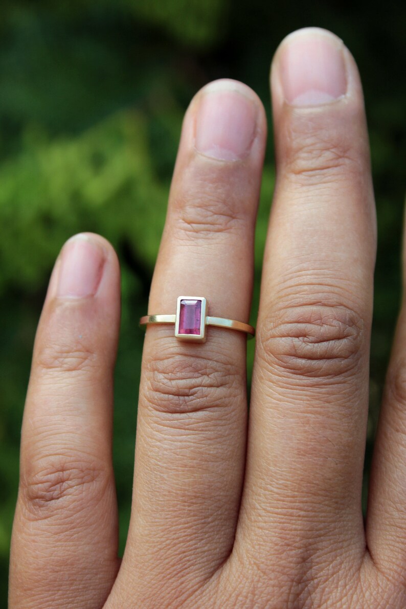 May include: A gold ring with a rectangular pink gemstone.
