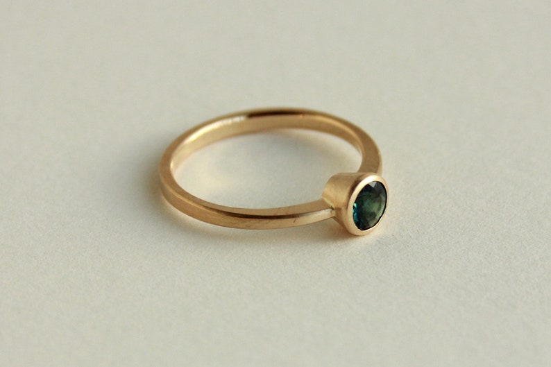 May include: A gold ring with a single round green gemstone.