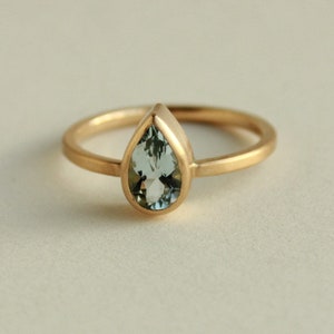 May include: A gold ring with a pear-shaped aquamarine gemstone.