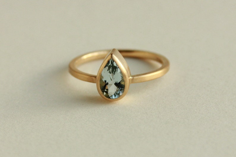 May include: A gold ring with a pear-shaped aquamarine gemstone.