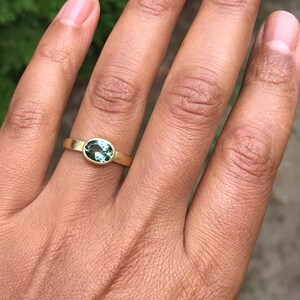 May include: A gold ring with a green oval gemstone set in a bezel setting.