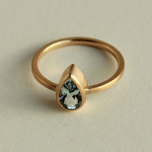 May include: A gold ring with a pear-shaped aquamarine gemstone.