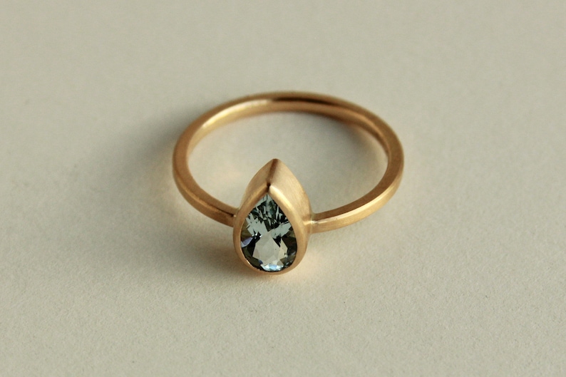 May include: A gold ring with a pear-shaped aquamarine gemstone.