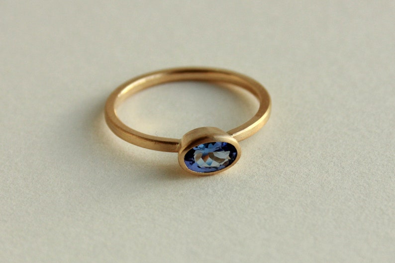May include: A gold ring with a blue oval gemstone.