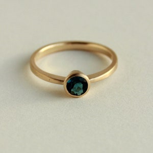 May include: A gold ring with a dark blue gemstone set in a bezel setting.