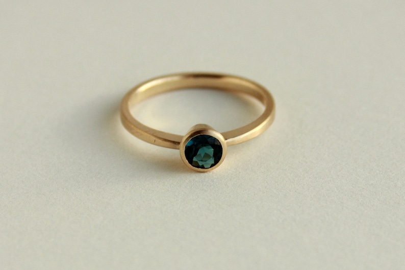 May include: A gold ring with a dark blue gemstone set in a bezel setting.