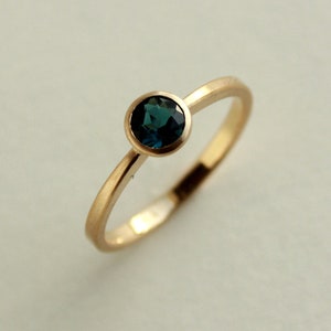 May include: A gold ring with a dark blue gemstone set in a bezel setting.