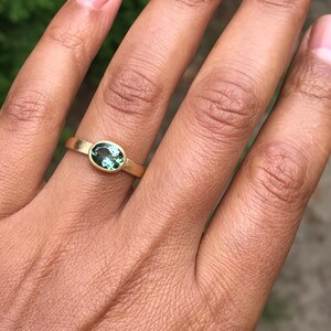 May include: A gold ring with a green oval gemstone set in the center.
