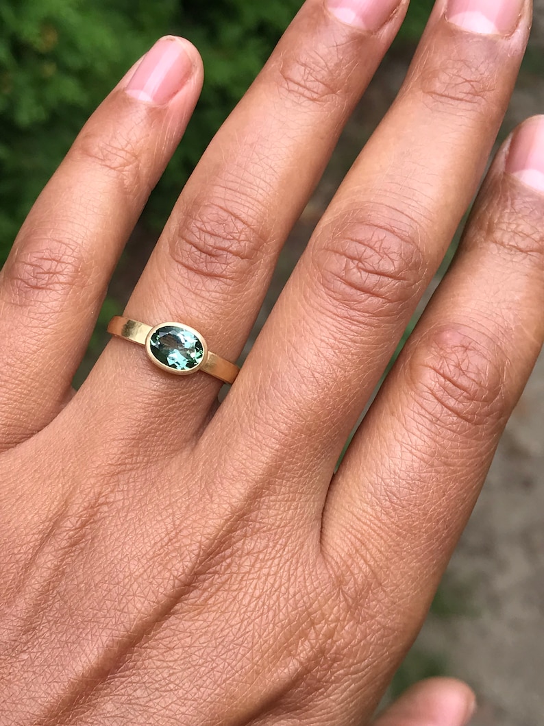 May include: A gold ring with a green oval gemstone set in the center.
