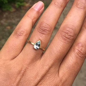May include: A gold ring with a teardrop-shaped blue gemstone.