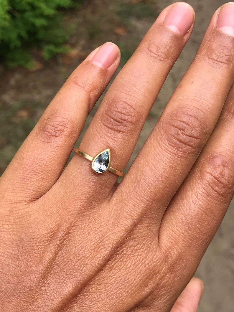 May include: A gold ring with a teardrop-shaped blue gemstone.