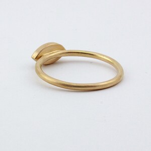 May include: A gold ring with a single, oval-shaped gemstone set in the center.