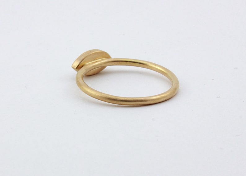May include: A gold ring with a single, oval-shaped gemstone set in the center.
