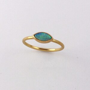 May include: A gold ring with a marquise-shaped opal gemstone. The opal is a light blue-green color.