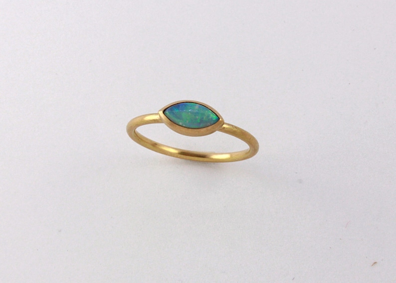 May include: A gold ring with a marquise-shaped opal gemstone. The opal is a light blue-green color.