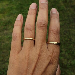 以下が含まれることがあります： 2つの金の結婚指輪をした手。指輪はシンプルでプレーンです