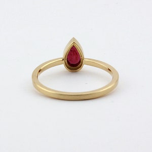 May include: A gold ring with a pear-shaped red gemstone.