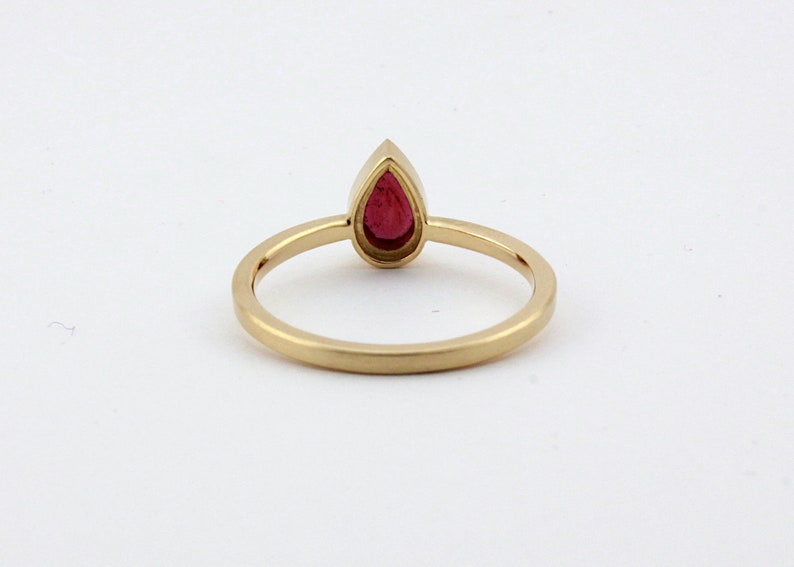 May include: A gold ring with a pear-shaped red gemstone.