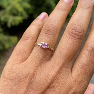 May include: A gold ring with a pink rectangular gemstone.