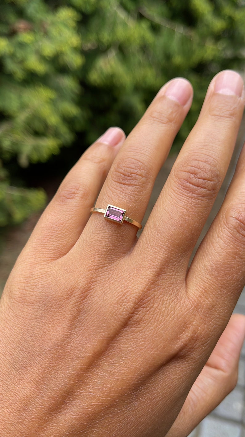 May include: A gold ring with a pink rectangular gemstone.