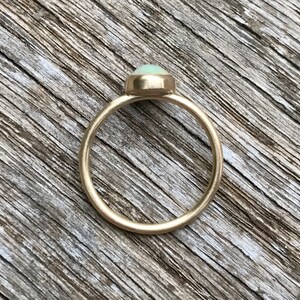 Pu&ograve; includere: Un anello d'oro con una pietra di opale ovale di colore verde chiaro.