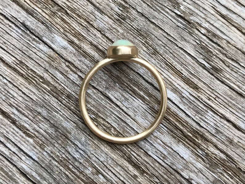 Pu&ograve; includere: Un anello d'oro con una pietra di opale ovale di colore verde chiaro.