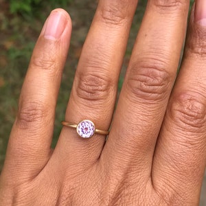 May include: A gold ring with a round, purple gemstone.