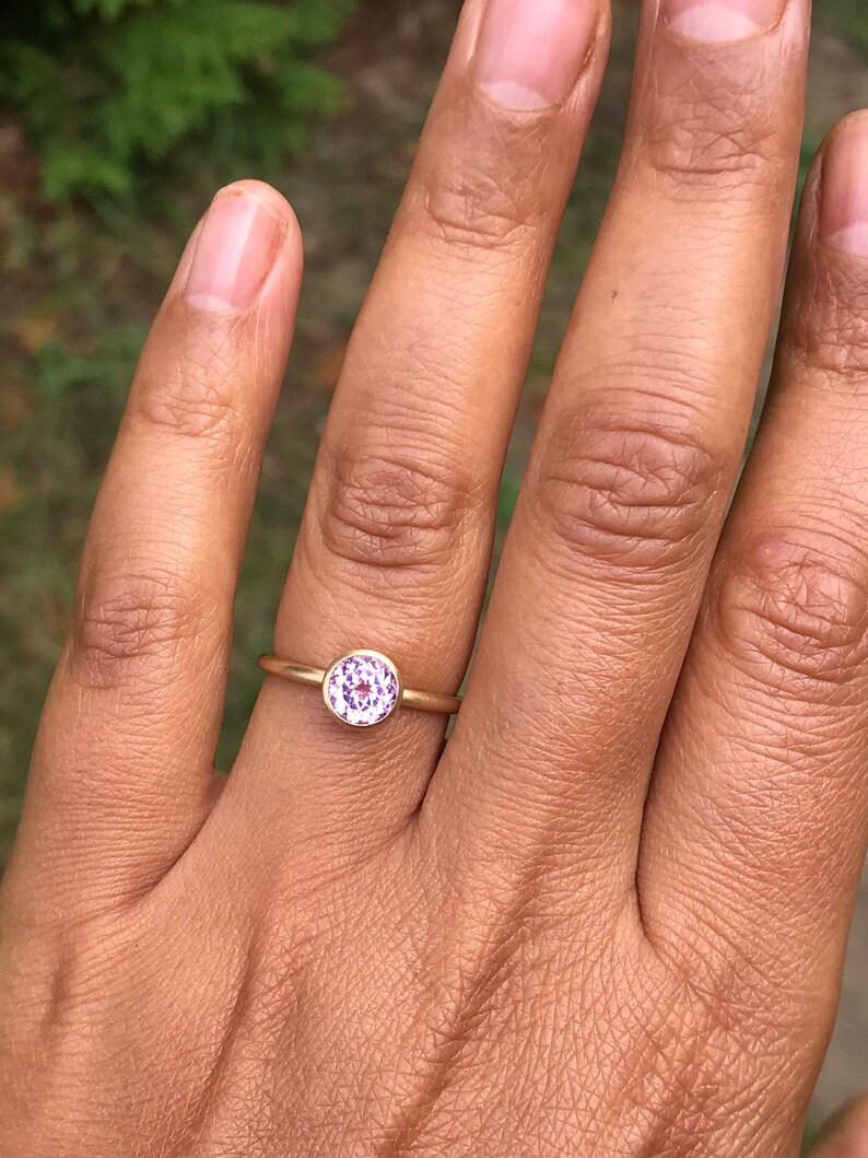 May include: A gold ring with a round, purple gemstone.