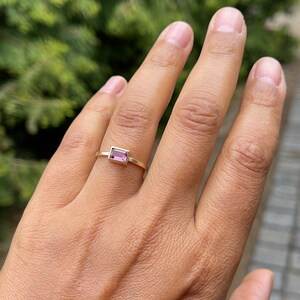 May include: A gold ring with a pink rectangular gemstone.