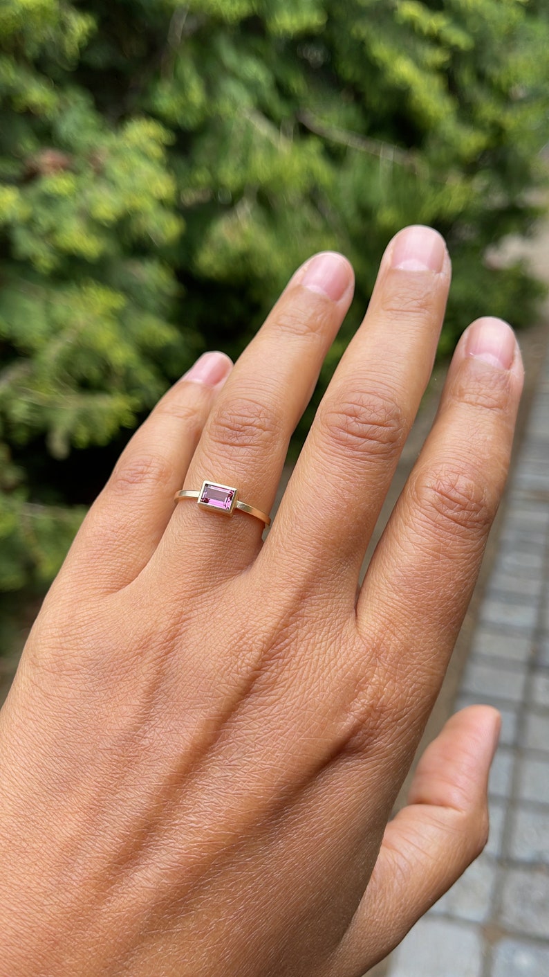 May include: A gold ring with a pink rectangular gemstone.