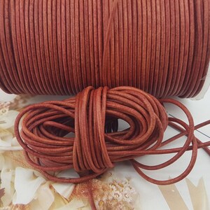 Può includere: Un rotolo di cordoncino in pelle marrone. Il cordoncino è avvolto strettamente attorno al rotolo ed è pronto per essere utilizzato per progetti di artigianato.