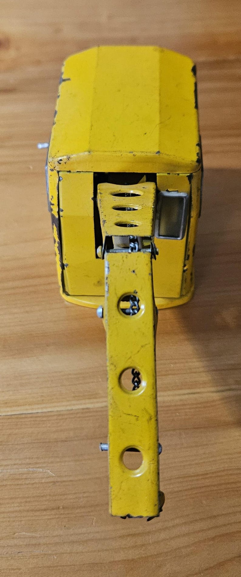 K&ouml;nnte beinhalten: Ein gelber Spielzeugkran mit einer Metallkette und einem beweglichen Arm. Der Kran hat ein kleines Fenster an der Seite und ist aus Metall.