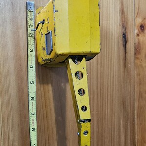 K&ouml;nnte beinhalten: Ein gelber Spielzeugkran aus Metall mit einem langen Arm und einer Kette. Der Kran ist etwa 23 cm hoch.