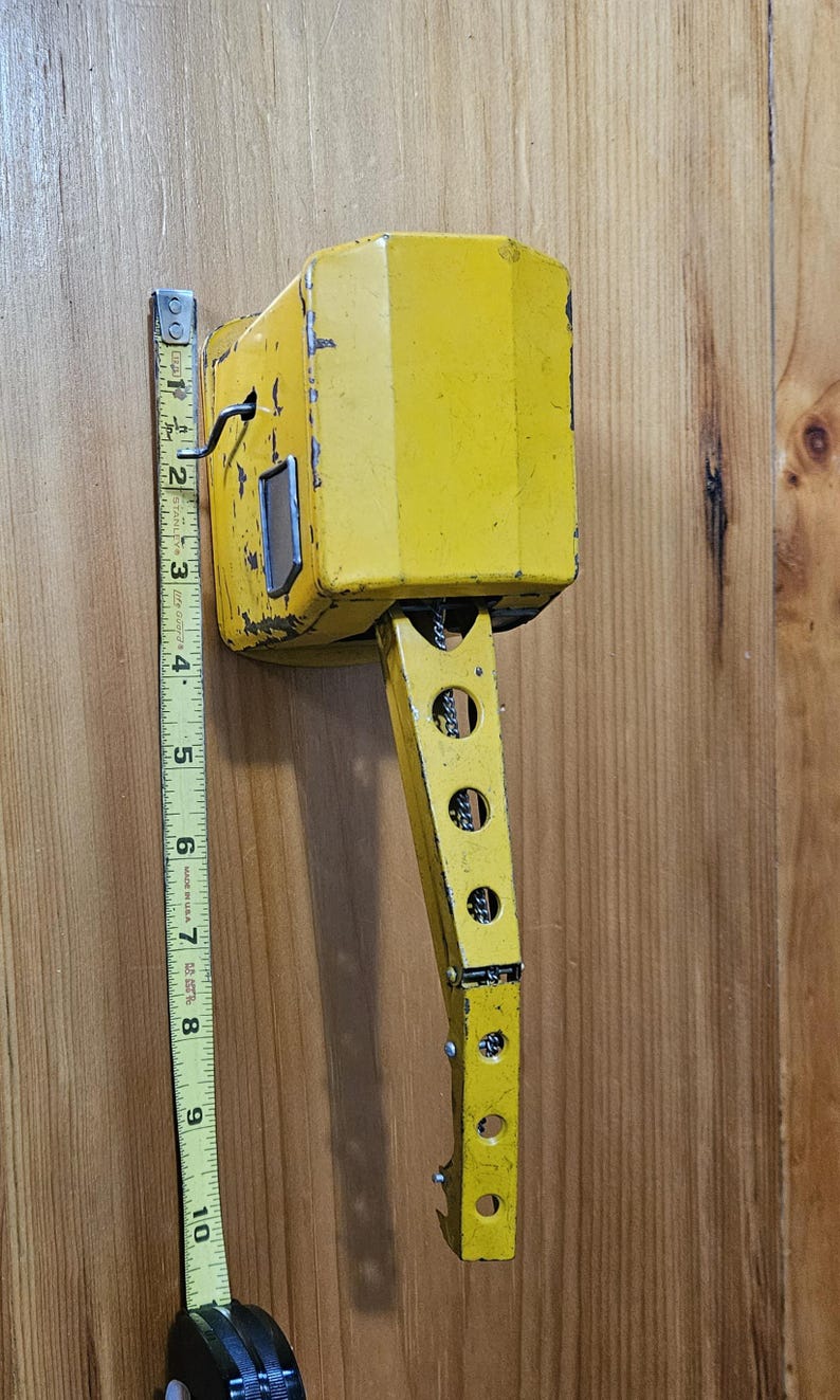 K&ouml;nnte beinhalten: Ein gelber Spielzeugkran aus Metall mit einem langen Arm und einer Kette. Der Kran ist etwa 23 cm hoch.
