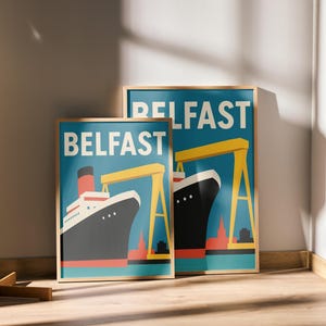 Könnte beinhalten: Zwei gerahmte Kunstdrucke mit einer stilisierten Illustration eines Schiffs und eines gelben Krans vor blauem Hintergrund. Das Wort "BELFAST" ist weiß gedruckt. Die Drucke sind in Holzrahmen und lehnen an einer Wand.
