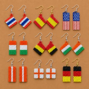 May include: A collection of beaded earrings featuring various flag designs. The earrings showcase the flags of the United States, Germany, Spain, and other countries. Each pair has a unique shape and color scheme, with silver or gold-colored hooks.
