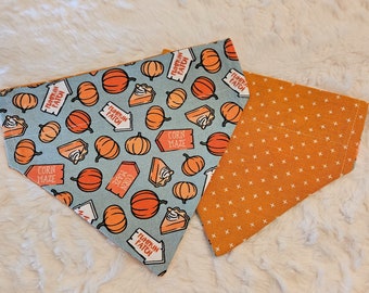May include: A blue and orange reversible dog bandana with a pumpkin patch and corn maze print. The bandana features the text "Pumpkin Patch" and "Corn Maze".