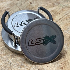 May include: A set of six silver coasters with a black rubber handle and the word "LSX" printed on each coaster.