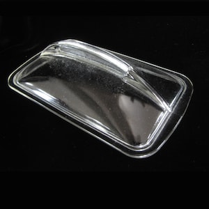 May include: A clear, rectangular glass lid with a curved handle. The lid has a slightly raised, rounded edge and is designed to fit over a rectangular container. The glass is transparent, allowing visibility of the contents.