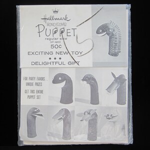 May include: A black and white image of a package for Hallmark Honeycomb Puppets. The package shows a variety of puppets, including a snake, a dog, and a bird. The text on the package reads "Hallmark Honeycomb Puppet, regular size (all ages) 50¢, Exciting New Toy, Delightful Gift, For Party Favors, Unique Prizes, Get This Entire Puppet Set."