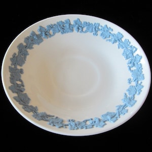May include: A white ceramic bowl with a light blue floral design around the rim. The bowl has a simple, elegant design, with the blue floral pattern providing a decorative accent. The bowl is likely used for serving food.
